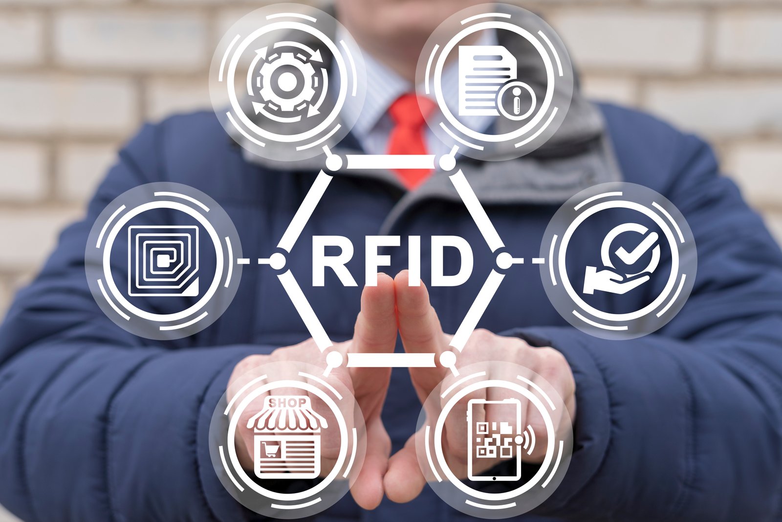Gráfico de RFID con iconos que representan diferentes aplicaciones de la tecnología RFID, incluyendo inventarios, gestión de productos y validación de procesos, conectados mediante una red hexagonal. Un fondo borroso muestra una figura humana de traje que interactúa con el concepto tecnológico.