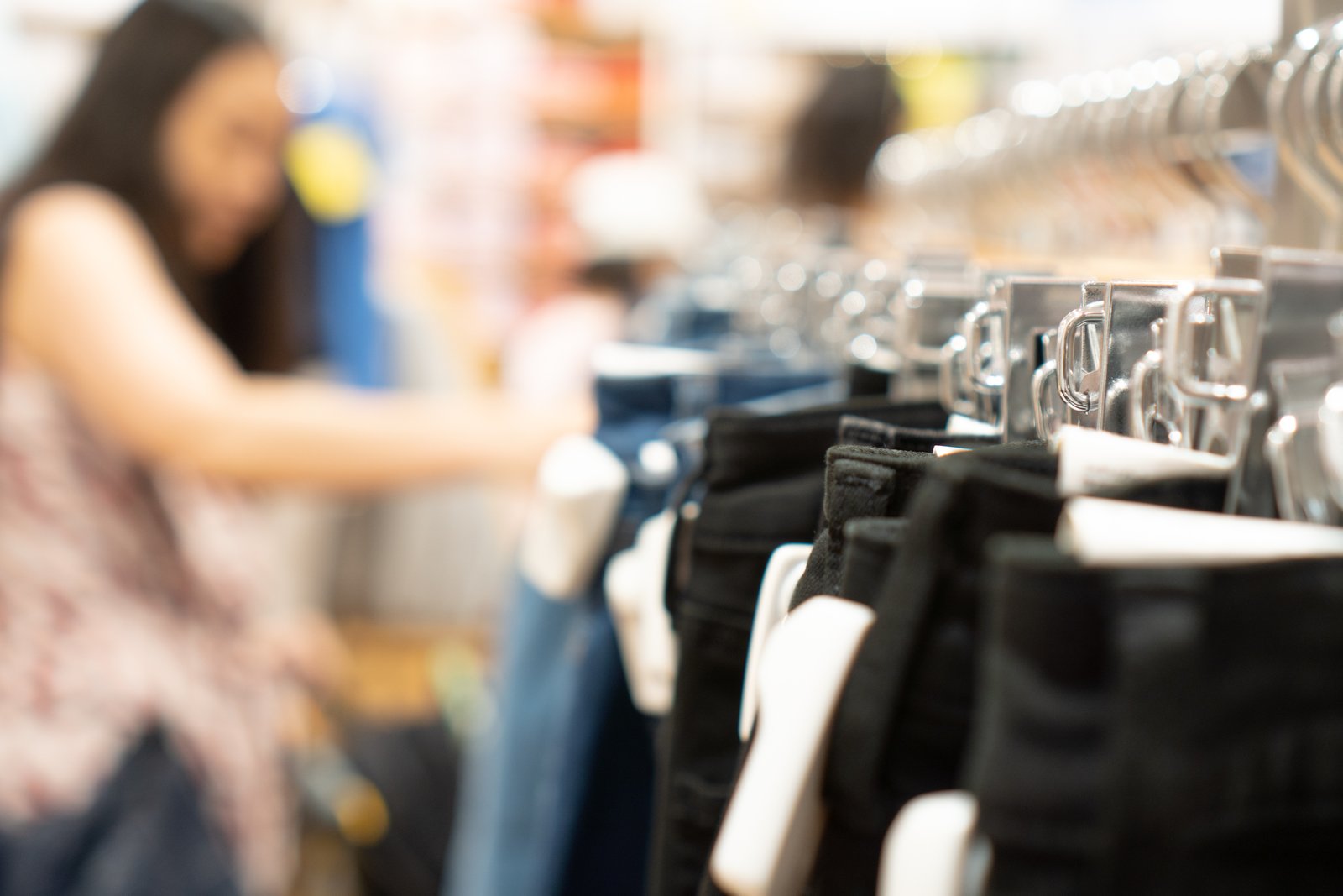 Ropa colgada en perchas con dispositivos de seguridad adheridos a cada prenda, utilizada para la prevención de robos en tiendas de retail.